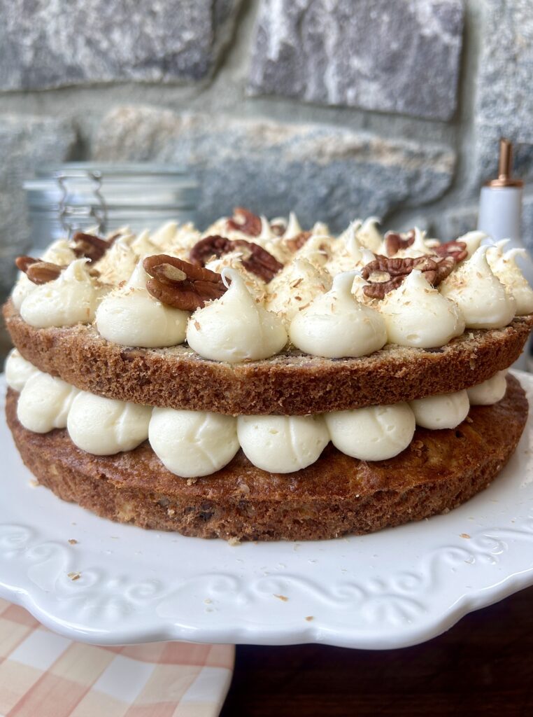 a white cake plate with a banana cake with cream cheese icing