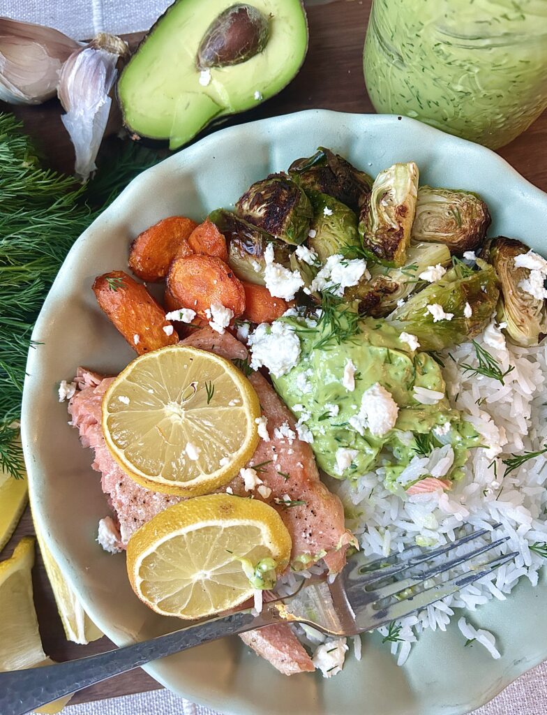 a rice bowl with carrot, Brussel sprouts, salmon and a creamy avocado dill sauce