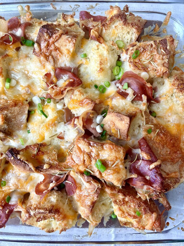 a baking dish with golden bread, gooey cheese and ham