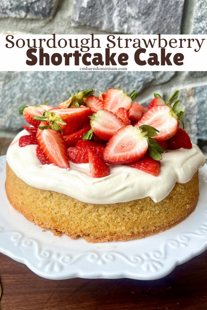a vanilla cake on a white cake stand with whipped cream and strawberries