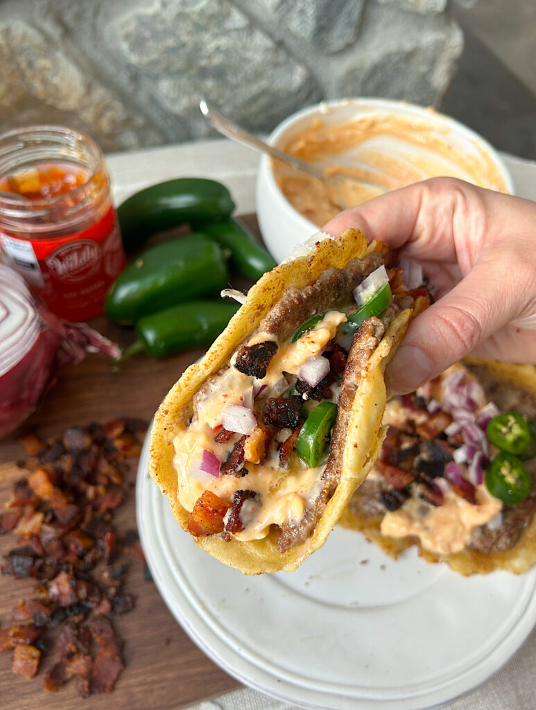 a taco with ground meat, creamy sauce, jalapeños and bacon