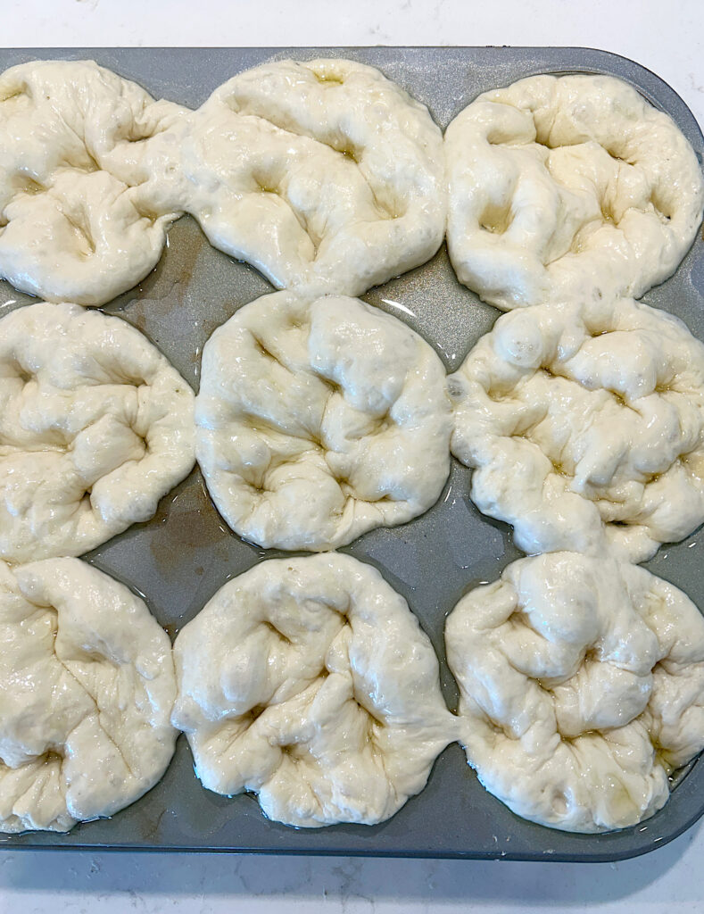 focaccia dough dimpled in a muffin tin