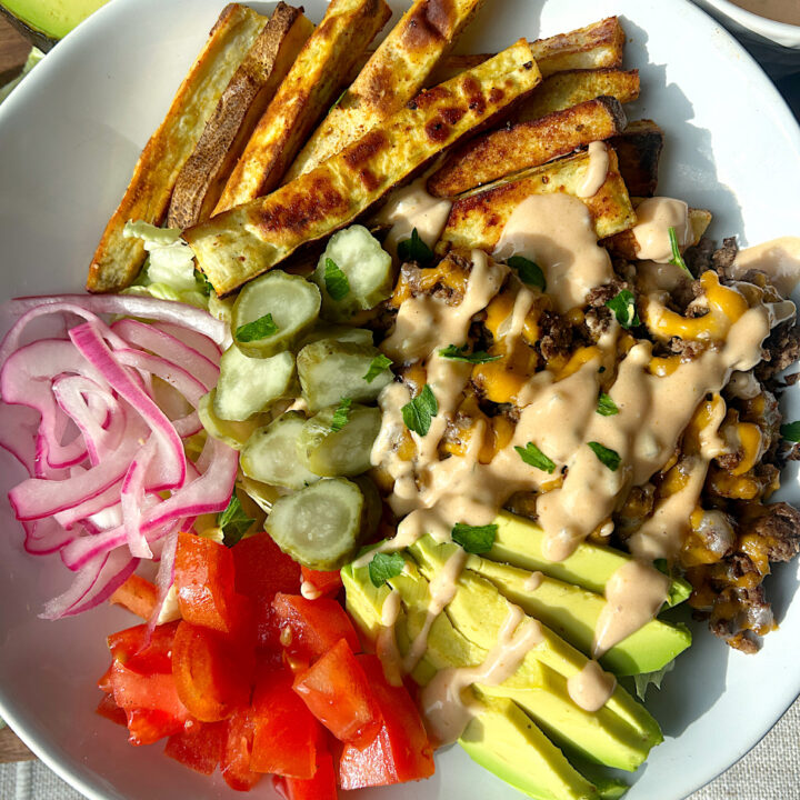 a bowl of ground meat, potato fries, burger toppings and burger sauce