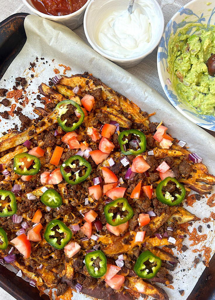 a baking sheets of potato nachos with venison and jalapeños 