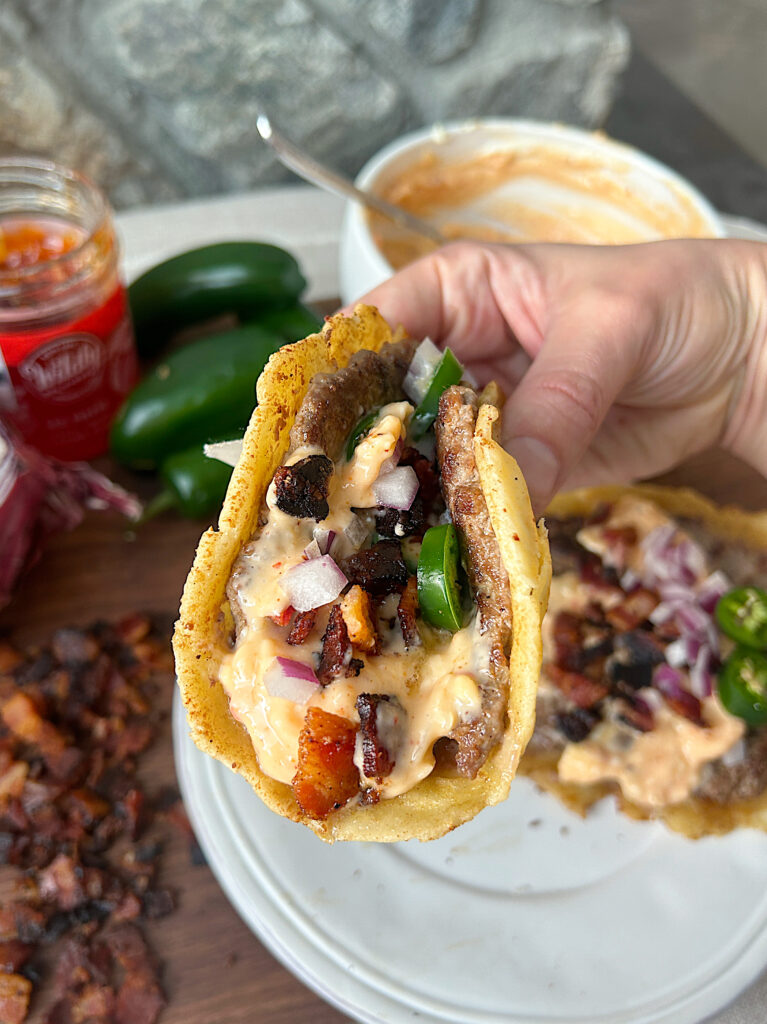 a smash burger tacos with jalapeños, bacon and cheese sauce