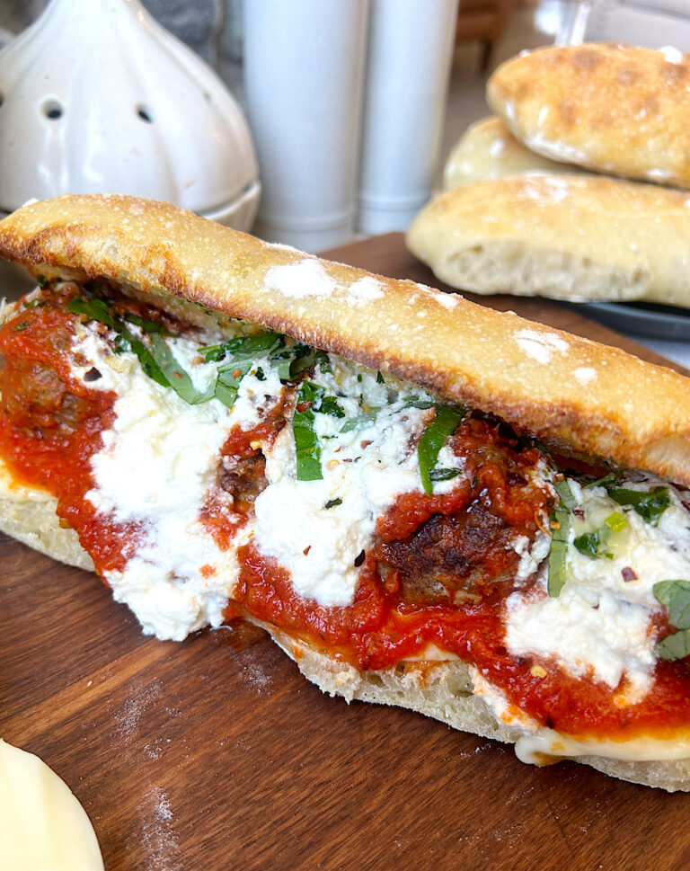 a sub sandwich filled with meatballs, tomato sauce and mozzarella