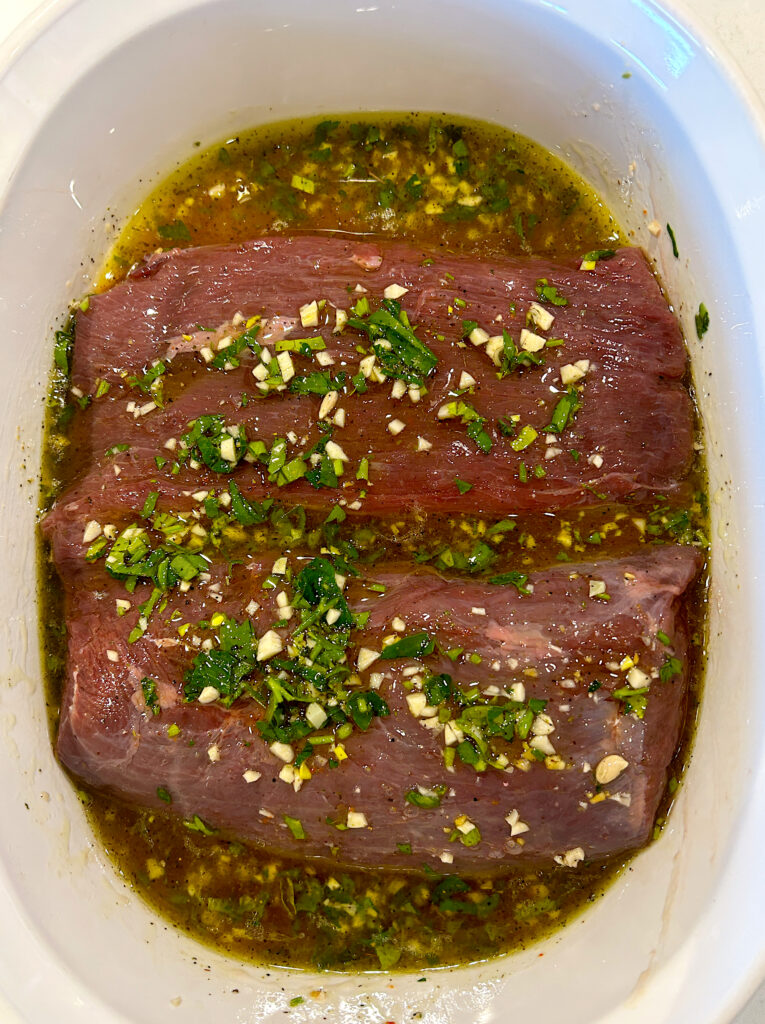 a venison roast, sitting in a garlic herb marinade