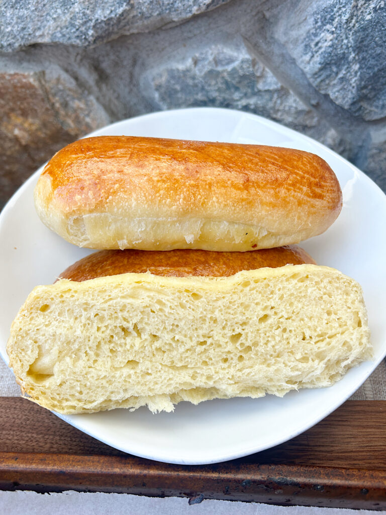 a white plate with sourdough hot dog buns