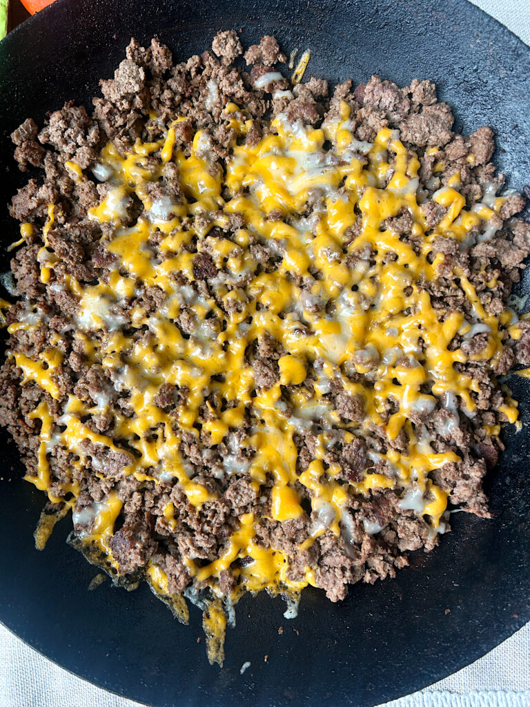 a skillet of ground venison with cheese on top