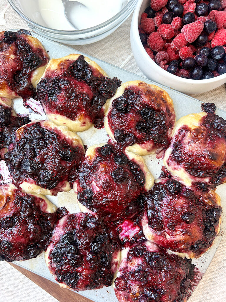 a muffin tray with berry sourdough muffins