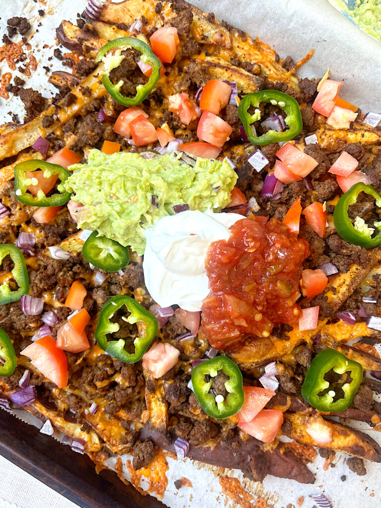 a sheet pan full of fries with cheese, ground meat and nacho toppings