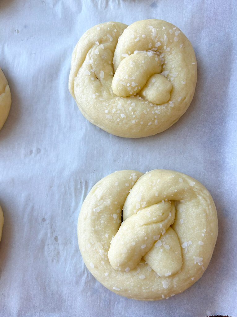 unbaked sourdough soft pretzels with sea salt on a baking sheet