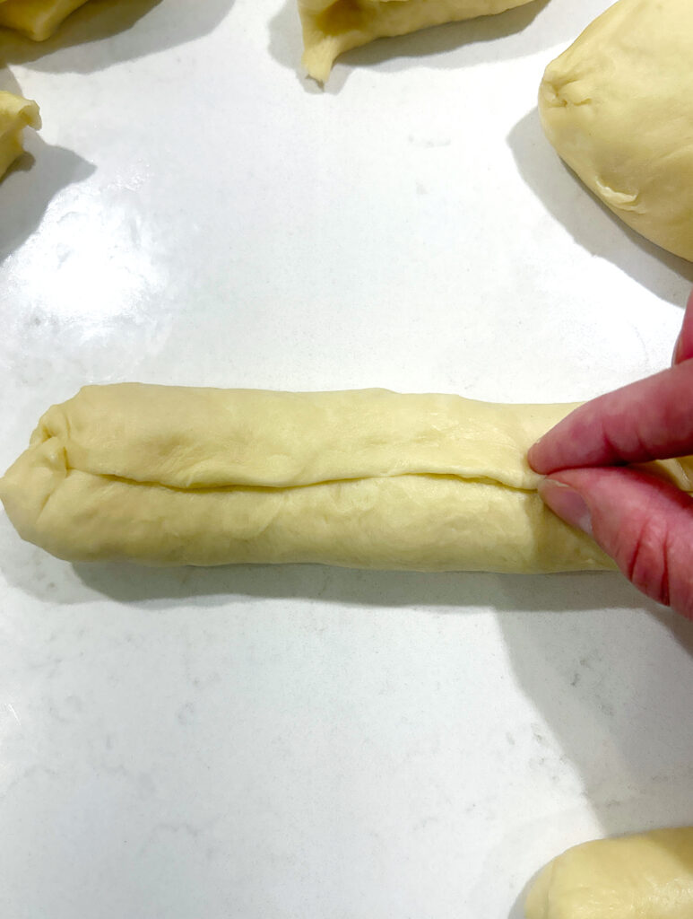 hot dog bun dough being pinched in a log