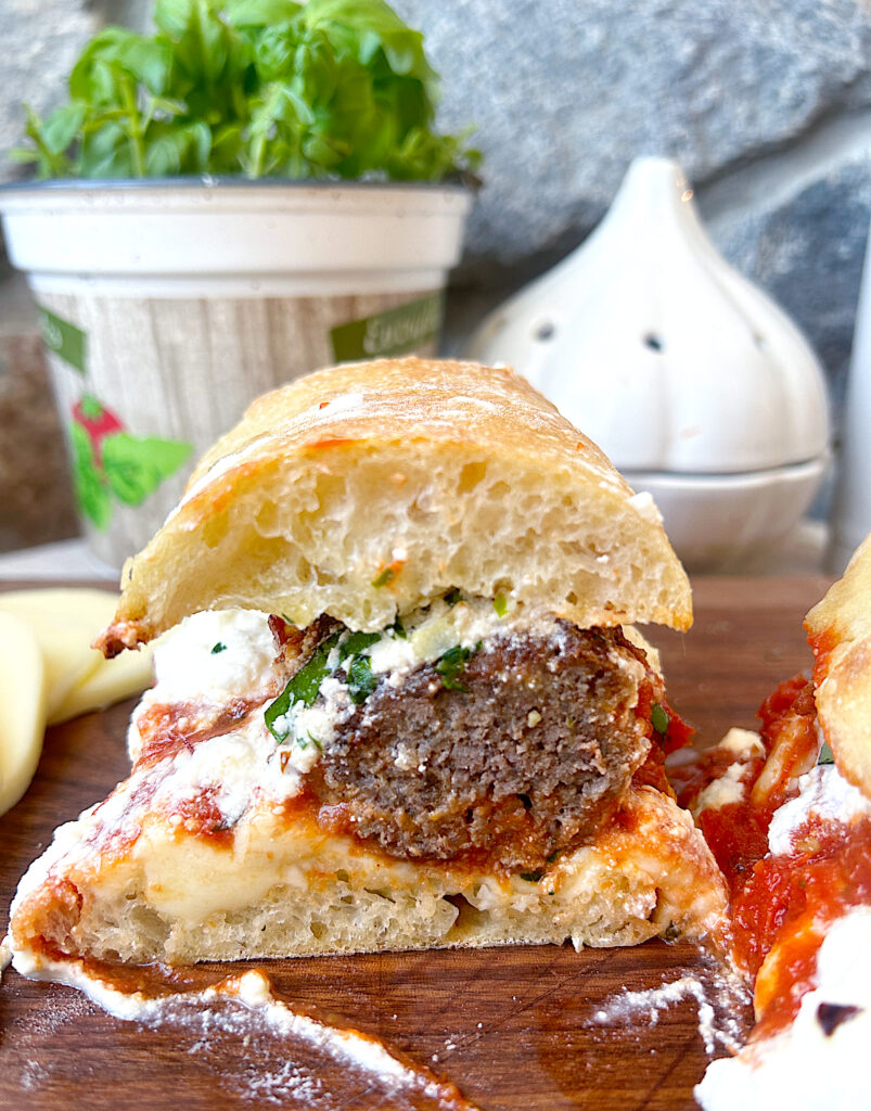 a meatball sandwich with tomato sauce and mozzarella cheese