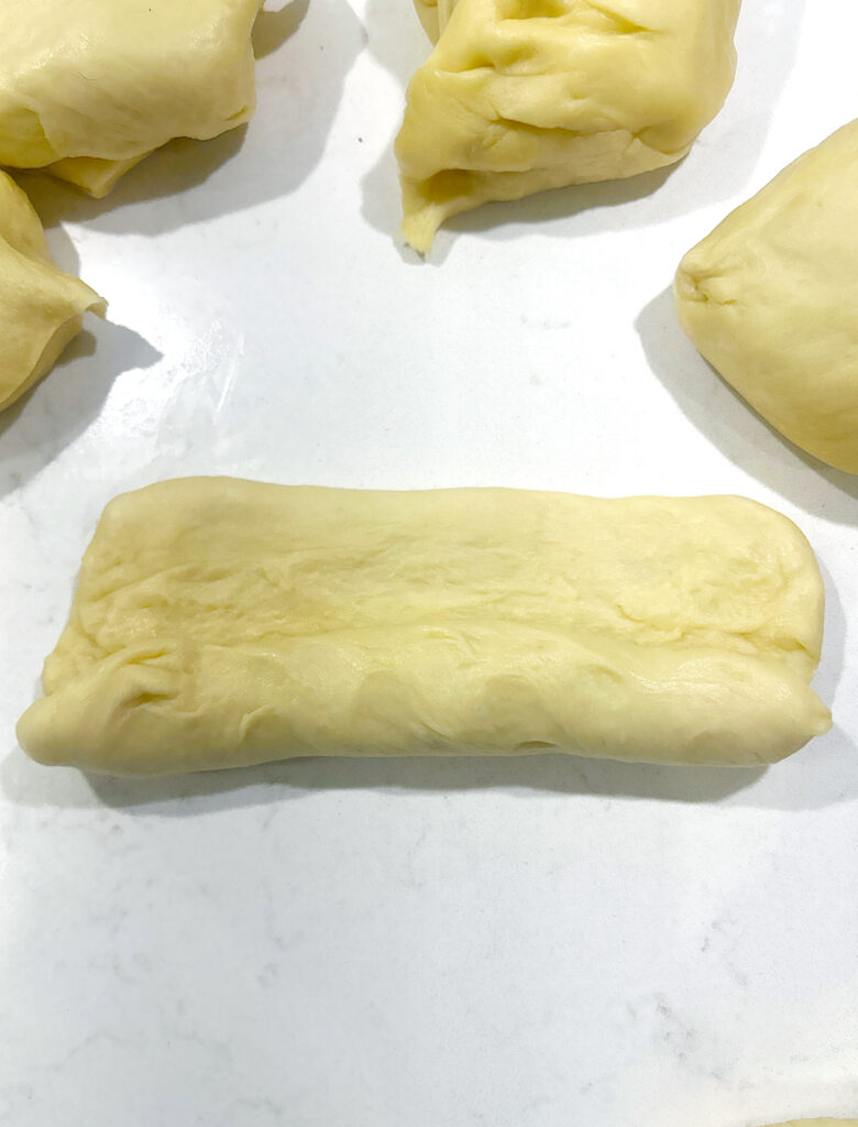 bun dough being rolled into a log