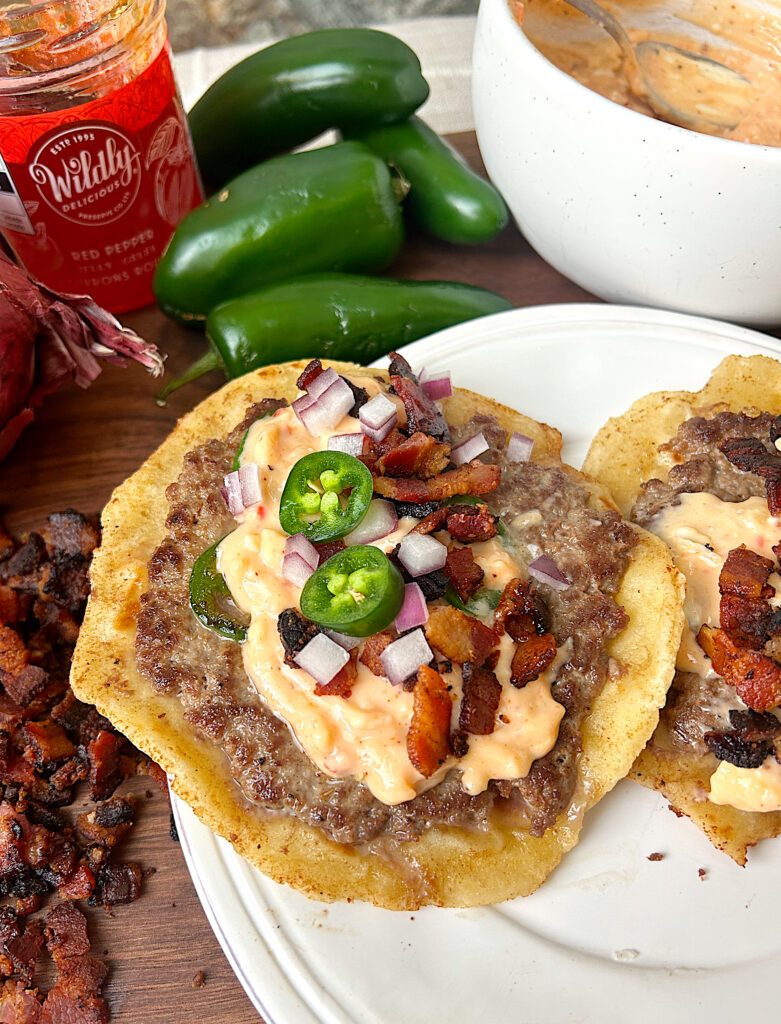 a soft tortillas with ground meat, bacon , red onion and jalapeños on it