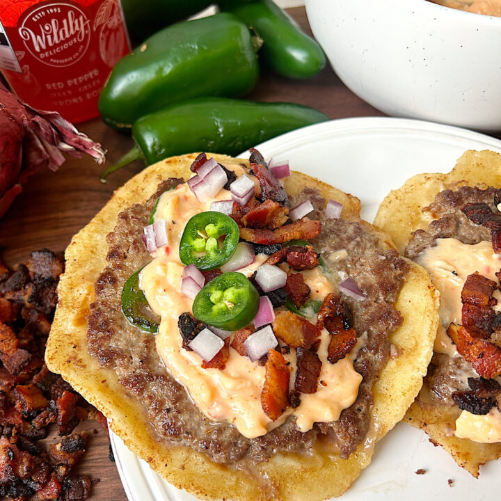 a soft tortillas with ground meat, bacon , red onion and jalapeños on it