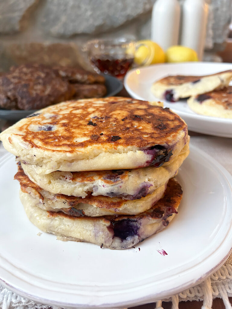 a white plate with a stack of blueberry pancakes