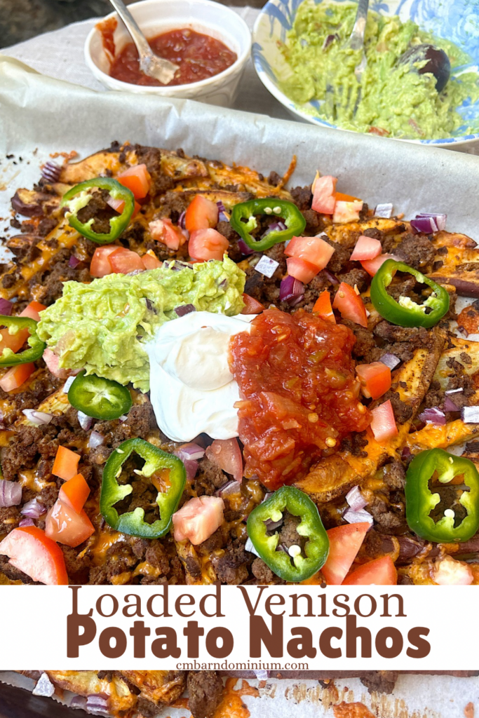 loaded nachos on a baking sheet with ground meat, jalapeños, sour cream, salsa and guacamole 