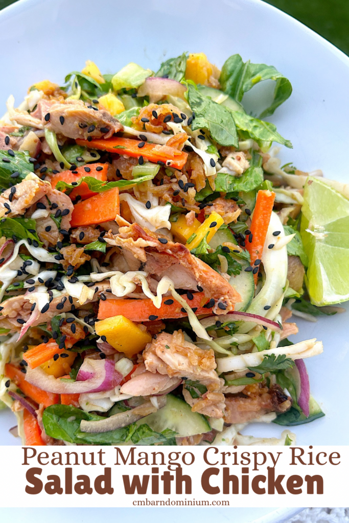 salad with chicken, carrots, mango, sesame and a peanut dressing in a white bowl
