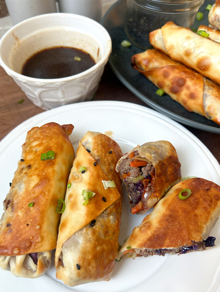 a white plate of crispy venison egg rolls
