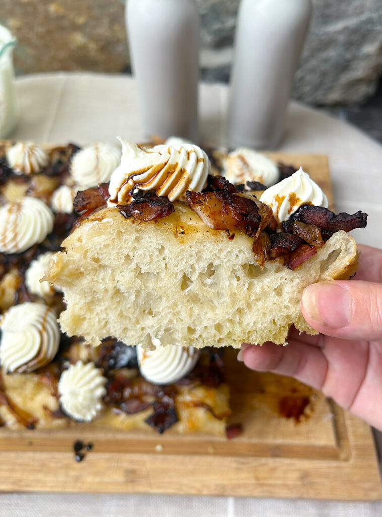 a slice of sourdough focaccia with bacon, onions and ricotta cheese on top