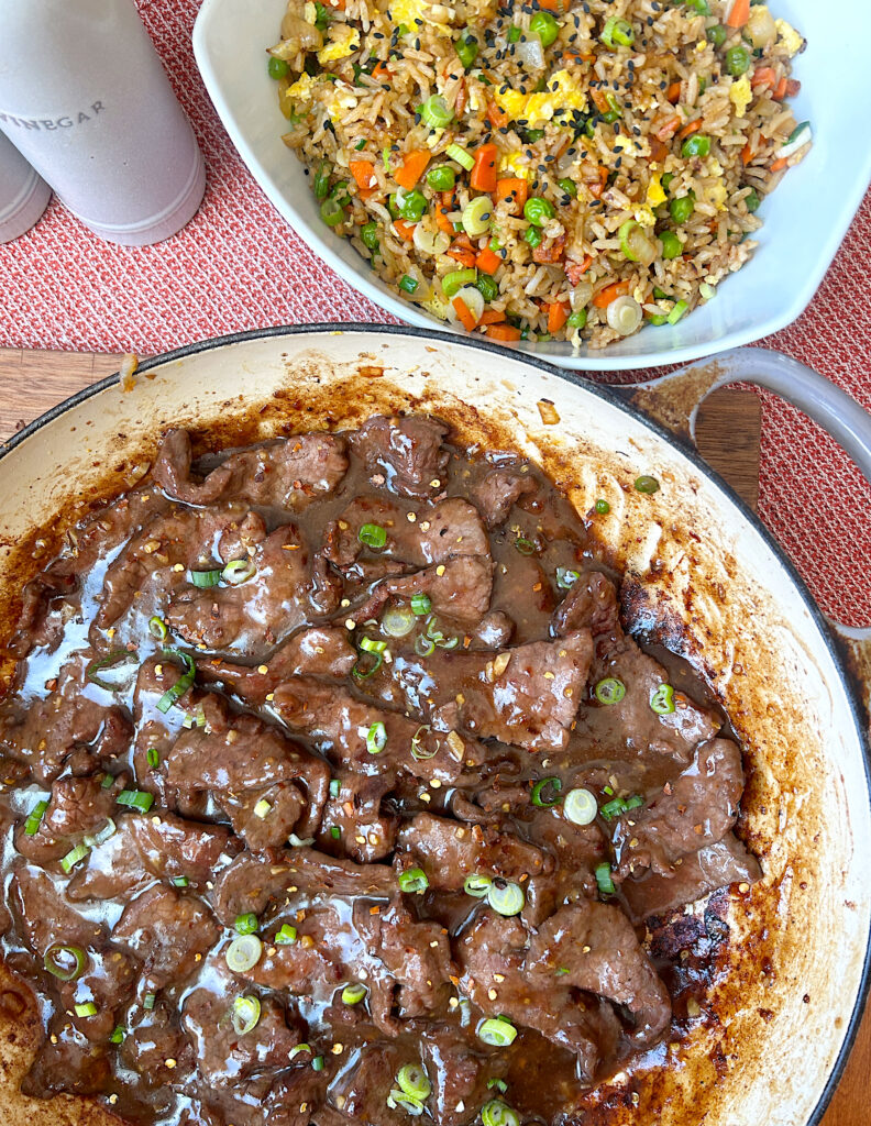 a skillet of venison stir fry with fried rice beside