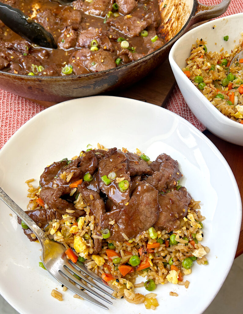 a white bowl of fried rice with sweet chili venison stir fry meat on top