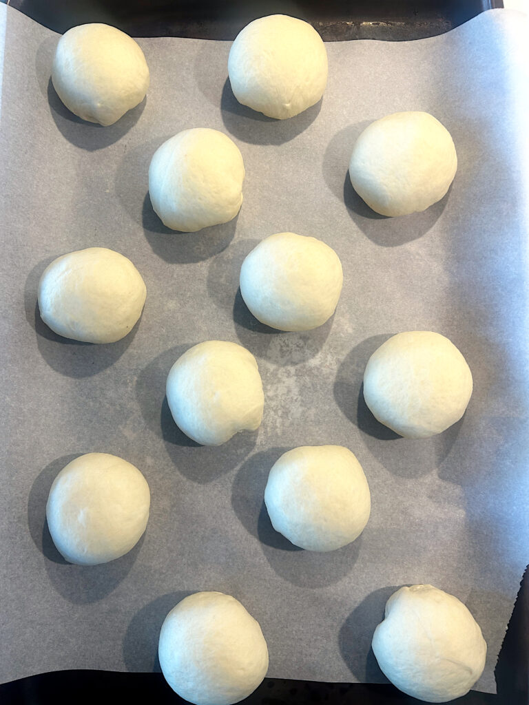 unbaked buns on a baking sheet
