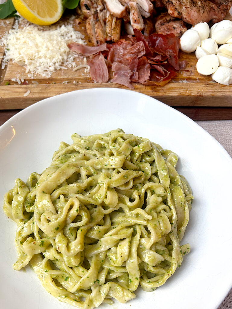 a white bowl of linguini with pesto sauce