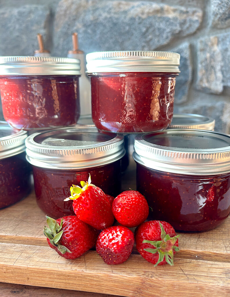 jars of strawberry jam stacked on a wood board
