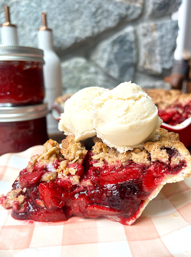 a slice of pie made with berries, and crumble topping, with ice cream on top