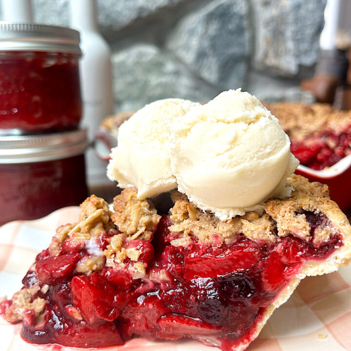 a slice of pie made with berries, and crumble topping, with ice cream on top