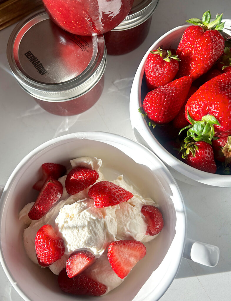 a white bowl of vanilla ice cream with strawberries on top