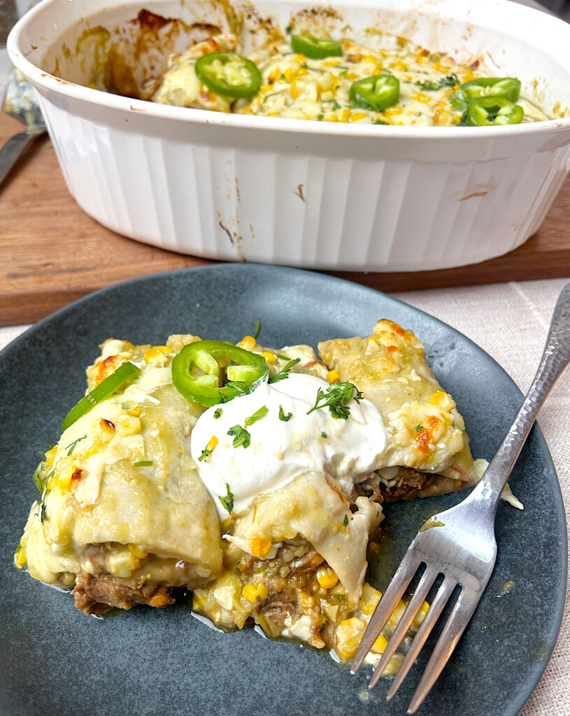 a blue plate with green enchiladas full of corn and venison