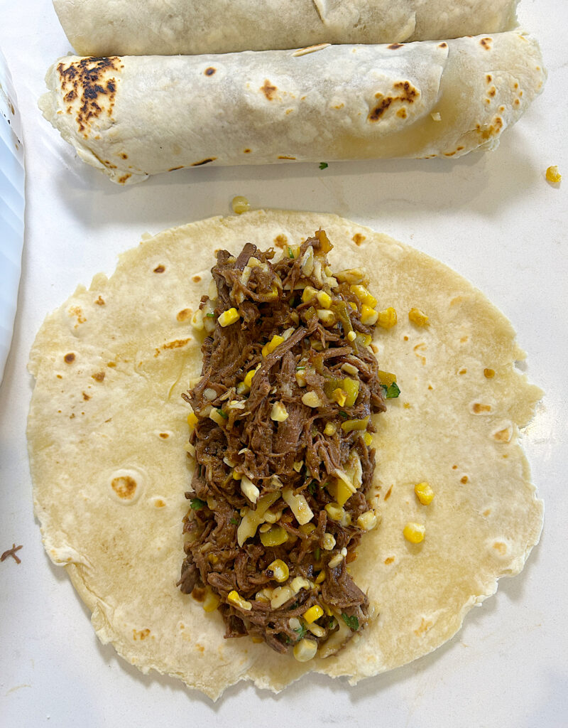 a tortilla with shredded venison and corn mixture on top