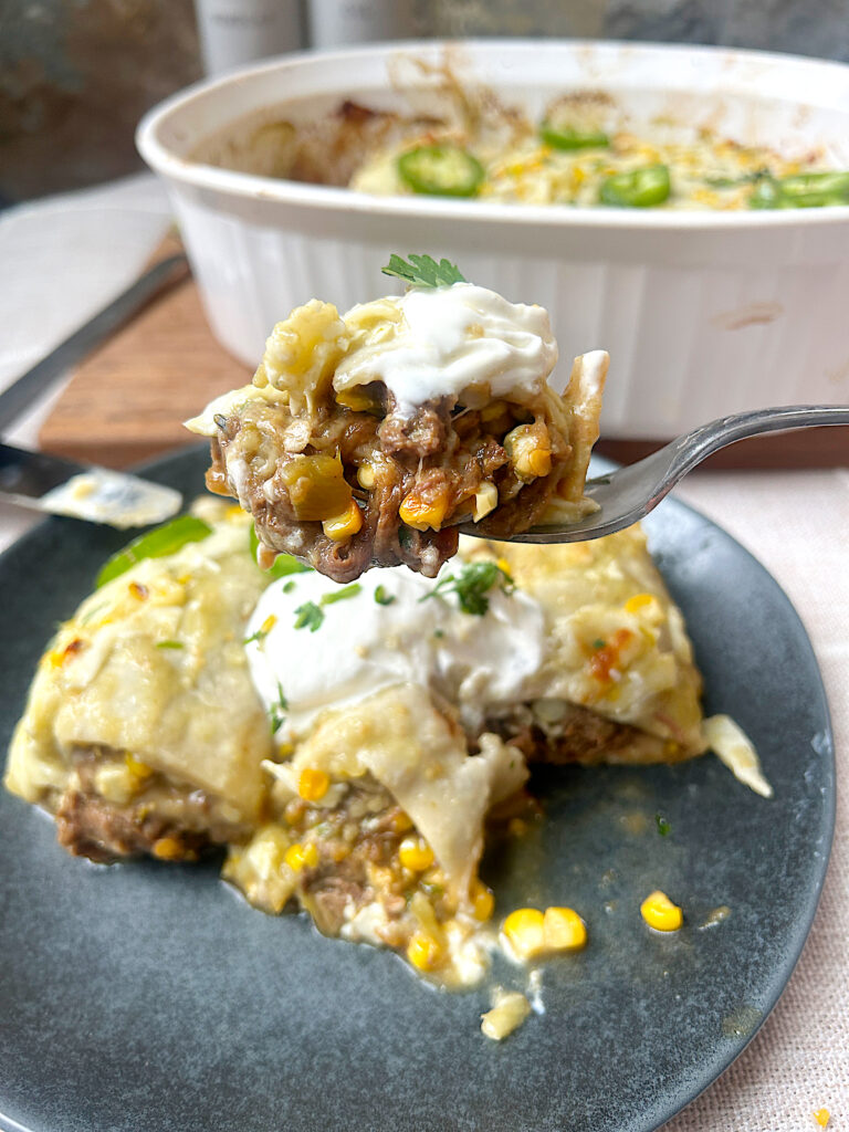 a blue plate of enchiladas full of shredded venison, corn and green chiles