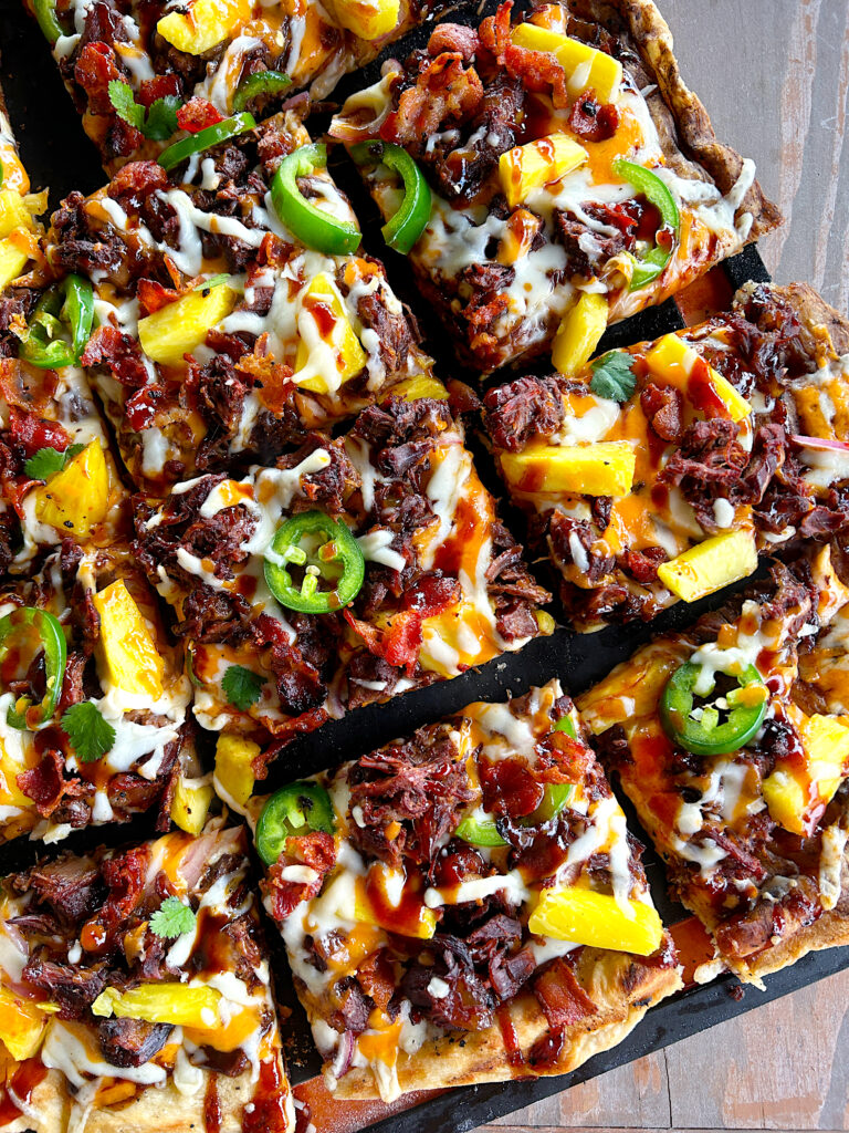 a grilled pizza with bbq meat, pineapples, cheese and jalapeños 