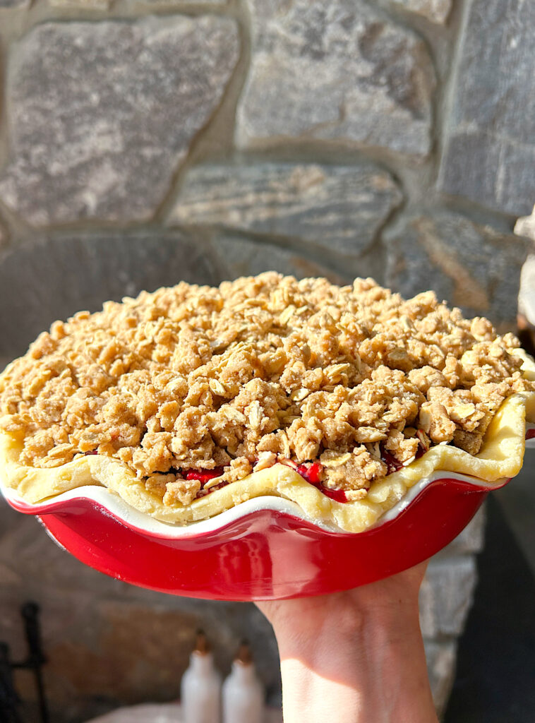 a red pie dish with a berry crumble pie