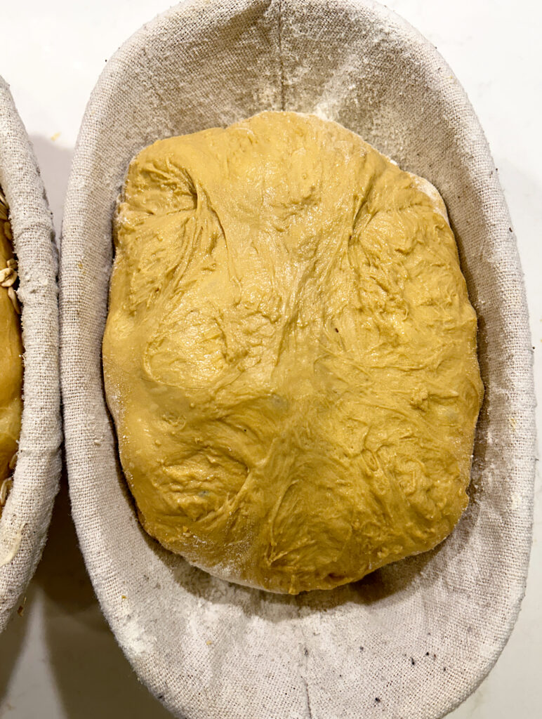 a baneton with a loaf of unbaked brown bread