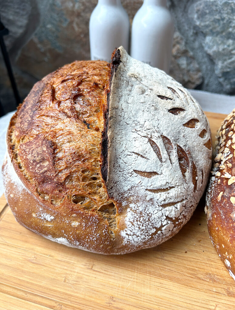 a loaf of molasses sourdough bread on a wood board