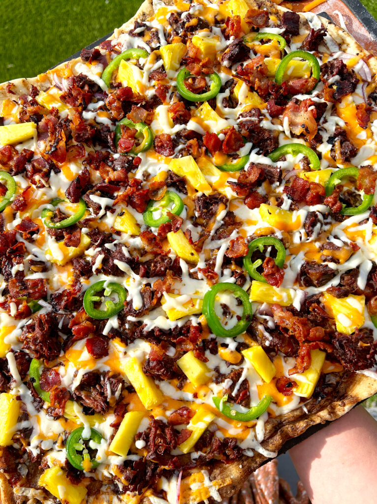 a flatbread with cheese, bacon, pineapple, meat a jalapeños 