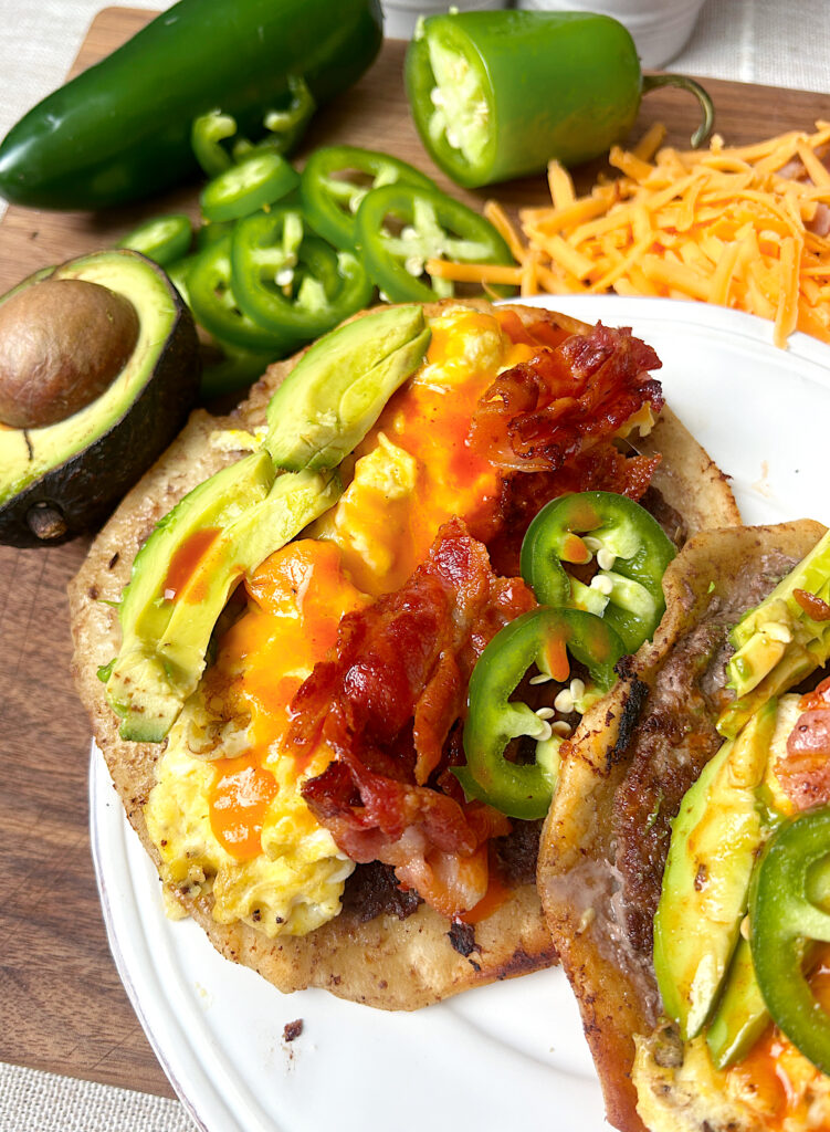 a soft taco with breakfast sausage, eggs, bacon, avocado and jalapeƱos
