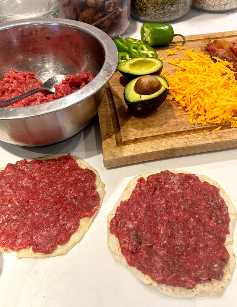 small tortillas with sausage meat spread on them