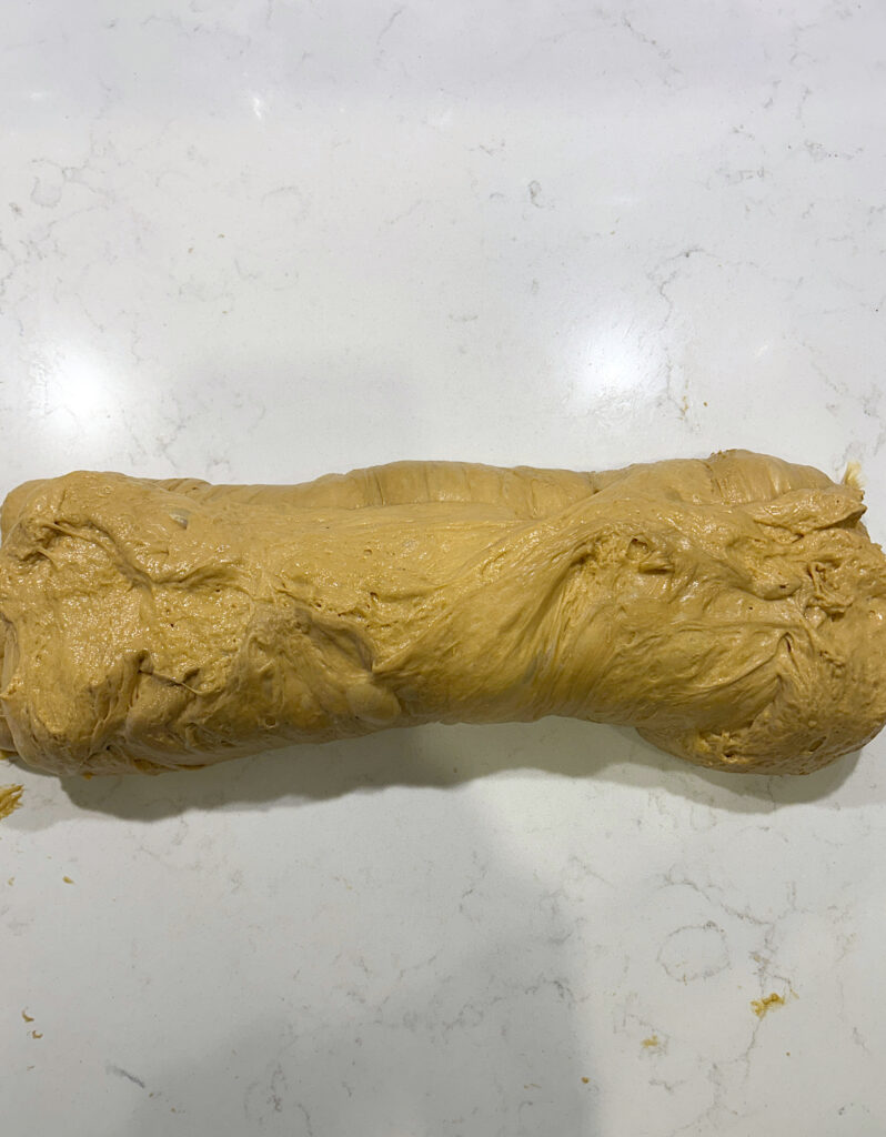 a log of brown bread dough on a white counter