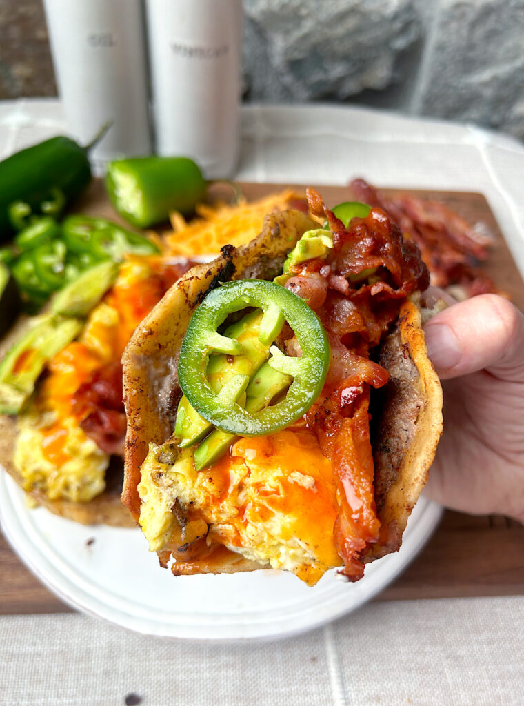 a breakfast taco with sausage, eggs, cheese, bacon and jalapeƱos