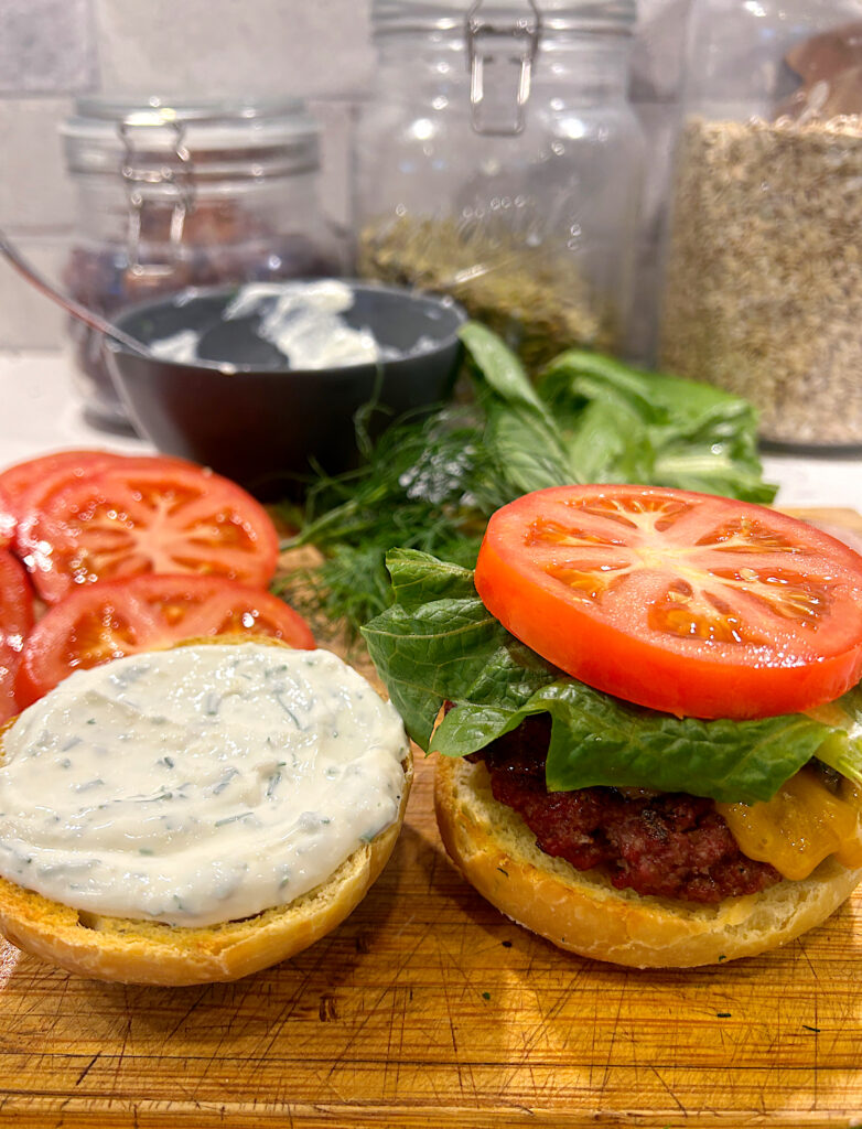a BLT burger with ranch sauce on a wood board