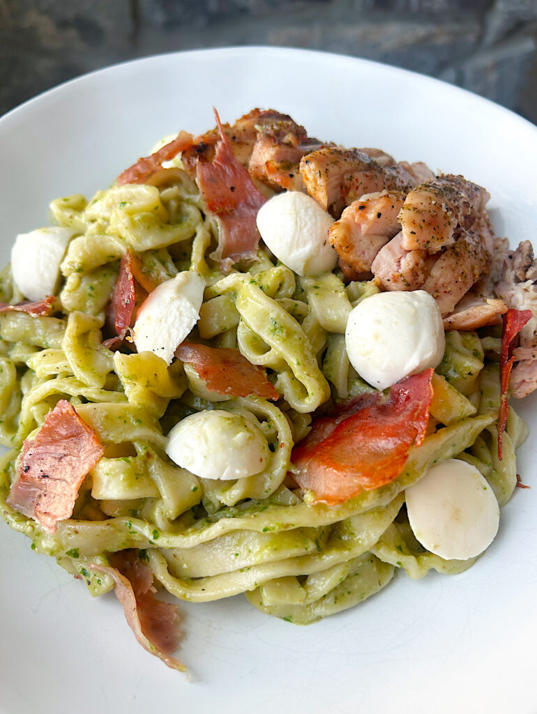 a bowl of homemade pasta with pest sauce, chicken, prosciutto and fresh mozzarella