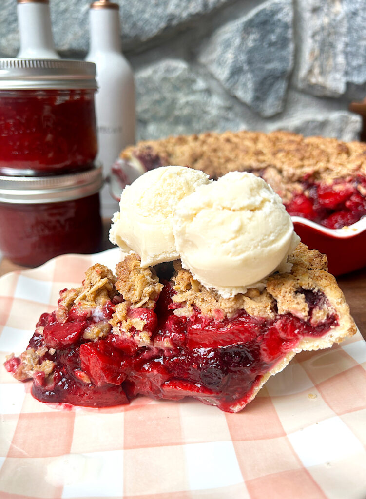 a slice of pie with mixed berry filling, crumble topping and vanilla ice cream
