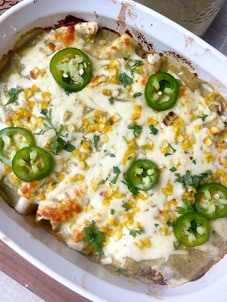 a baking dish of enchiladas with green Chile sauce and pepper jack cheese